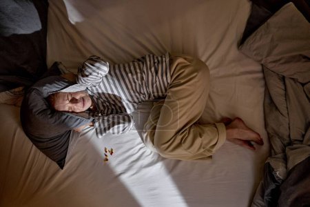 Foto de Mujer pelirroja deprimida asustada acostada sola en la cama en posición fetal cubriendo la cabeza con almohada sintiendo miedo deprimido sufren de abuso mental violencia - Imagen libre de derechos