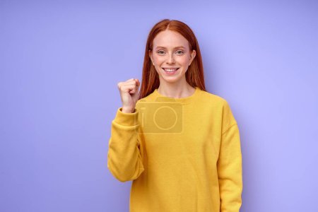 Photo for Young deaf mute woman using sign language on blue background, showing letter A, smiling girl with clenched fist looking at camera body language closeup portrait - Royalty Free Image