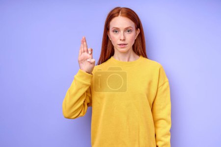 Foto de Hermosa pelirroja mujer demostrando letra F símbolo de lenguaje de señas para sordos humanos con fondo azul. aislado - Imagen libre de derechos