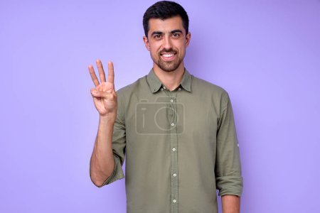 Téléchargez les photos : Homme barbu brune joyeux démontrant la lettre W w. symbole de langue des signes pour les sourds humains en fond bleu. isolé - en image libre de droit