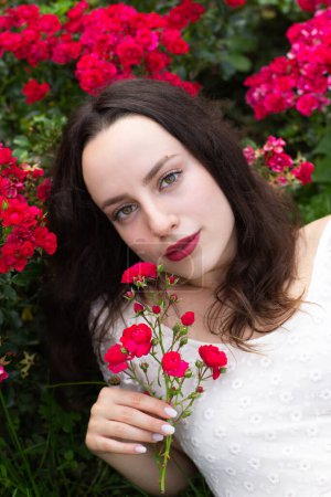 Foto de Una mujer románticamente atraída con un vestido blanco sostiene suavemente rosas. - Imagen libre de derechos