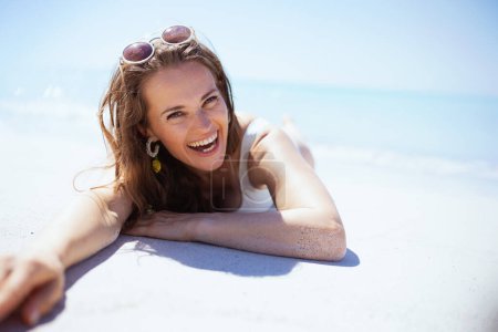 Portrait of happy modern woman laying at the beach.