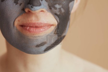 Foto de Primer plano en mujer de mediana edad con máscara facial sobre fondo beige. - Imagen libre de derechos