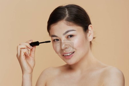 Photo for Portrait of modern asian woman with mascara on beige background. - Royalty Free Image