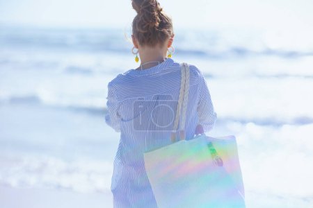 Photo for Seen from behind middle aged woman with white straw bag at the beach. - Royalty Free Image