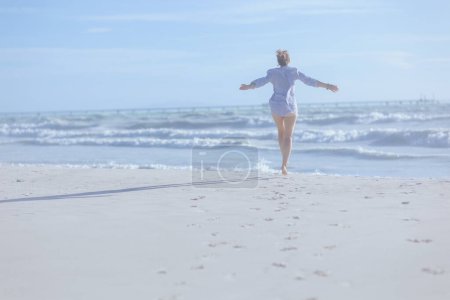 Téléchargez les photos : Vu de derrière femme à la plage se réjouissant. - en image libre de droit