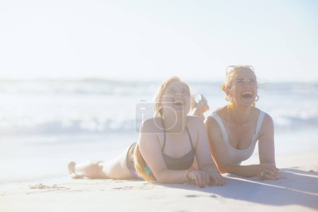 Foto de Feliz madre con estilo y la hija adolescente en traje de baño en la playa. - Imagen libre de derechos