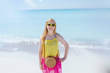 Téléchargez les photos : Heureux enfant moderne dans des lunettes de soleil à la plage en robe colorée. - en image libre de droit