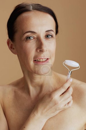 Foto de Retrato de mujer moderna con masajeador de rodillos sobre fondo beige. - Imagen libre de derechos