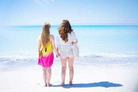 Photo for Seen from behind modern mother and child at the beach looking into distance. - Royalty Free Image