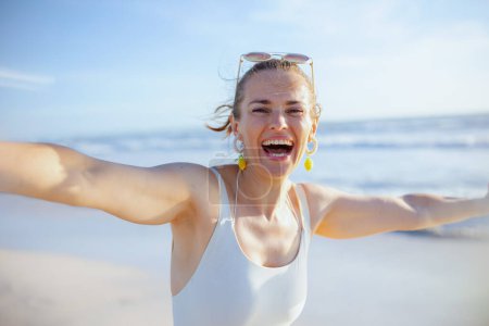 Photo for Smiling modern 40 years old woman in white swimwear at the beach having fun time. - Royalty Free Image