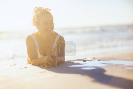 Téléchargez les photos : Heureux moderne femelle en blanc beachwear pose à la plage. - en image libre de droit