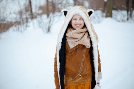 Photo for Portrait of smiling stylish girl in coat, hat, scarf and mittens outdoors in the city park in winter. - Royalty Free Image