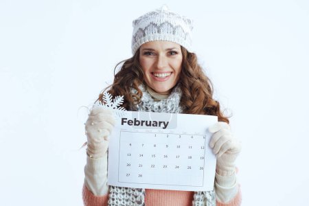 Téléchargez les photos : Bonjour l'hiver. Portrait de heureuse femme moderne en pull, mitaines, chapeau et écharpe sur fond blanc avec calendrier janvier et flocon de neige. - en image libre de droit