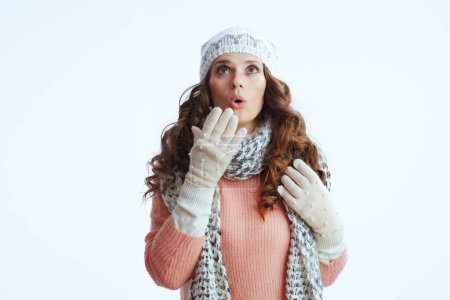 Photo for Hello winter. surprised trendy female in sweater, mittens, hat and scarf looking up on copy space isolated on white. - Royalty Free Image