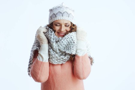 Téléchargez les photos : Bonjour l'hiver. femme moderne souriante en pull, mitaines, chapeau et écharpe enveloppant dans une écharpe isolée sur blanc. - en image libre de droit