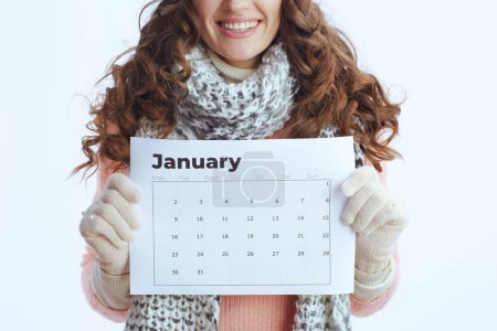 Photo for Hello winter. Closeup on trendy middle aged woman in sweater, mittens, hat and scarf with january calendar isolated on white. - Royalty Free Image