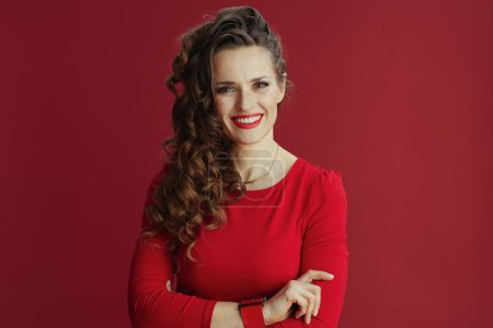 Téléchargez les photos : Joyeux Valentin. Portrait de femme élégante souriante avec de longs cheveux ondulés en robe rouge et béret sur fond rouge. - en image libre de droit