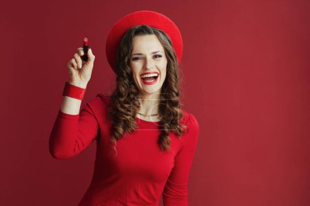 Foto de Feliz San Valentín. sonriente mujer moderna de 40 años en vestido rojo y boina sobre fondo rojo con lápiz labial rojo. - Imagen libre de derechos