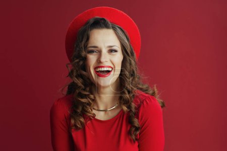 Photo for Happy Valentine. Portrait of happy modern middle aged woman with long wavy hair in red dress and beret on red background. - Royalty Free Image