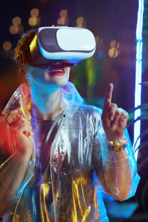 Foto de Mujer de moda feliz en realidad virtual en auriculares vr pulsando el botón en el aire. - Imagen libre de derechos