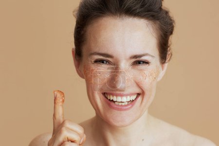 Photo for Happy modern middle aged woman with face scrub isolated on beige background. - Royalty Free Image