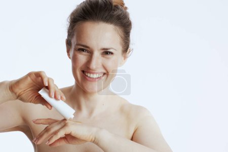 Foto de Feliz mujer moderna de 40 años con crema de manos aislada en blanco. - Imagen libre de derechos