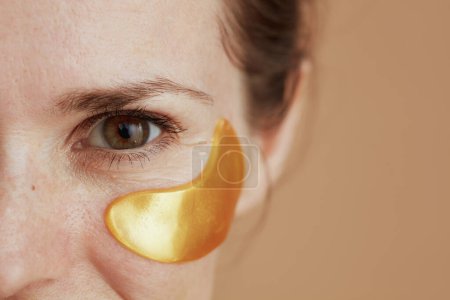 Photo for Closeup on young female with eye patches isolated on beige background. - Royalty Free Image