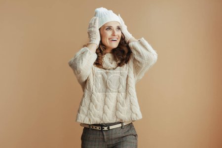 Téléchargez les photos : Bonjour l'hiver. femme élégante surprise en pull beige, mitaines et chapeau sur fond beige. - en image libre de droit