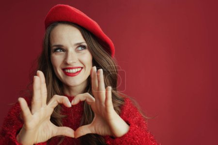 Photo for Happy Valentine. happy trendy middle aged woman in red sweater and beret showing heart shaped hands. - Royalty Free Image
