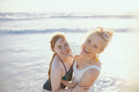 Foto de Retrato de la sonriente madre y el niño con estilo en la playa en ropa de playa divirtiéndose. - Imagen libre de derechos