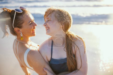 Téléchargez les photos : Heureux moderne mère et adolescente fille à la plage en maillot de bain avoir du plaisir. - en image libre de droit