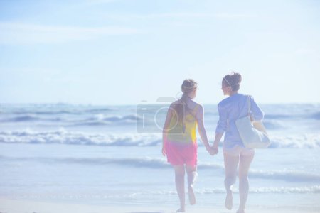 Foto de Visto desde detrás de la madre moderna y el niño en la playa corriendo. - Imagen libre de derechos