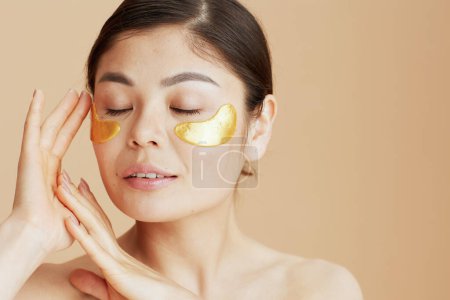 Photo for Relaxed modern asian woman with eye patches isolated on beige background. - Royalty Free Image