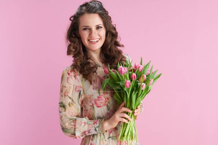 Photo for Happy young woman with long wavy brunette hair with tulips bouquet isolated on pink background. - Royalty Free Image