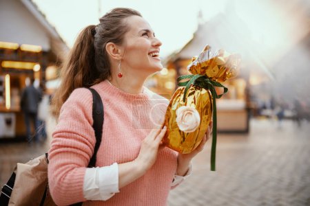 Photo for Easter fun. young woman in pink blouse with backpack and golden easter egg at the fair in the city. - Royalty Free Image
