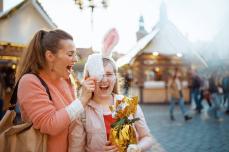 Foto de Easter fun. smiling young mother and child with golden easter egg at the fair in the city. - Imagen libre de derechos