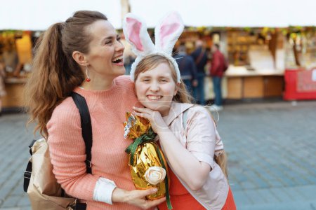 Foto de Easter fun. happy modern mother and teenage daughter with golden easter egg at the fair in the city. - Imagen libre de derechos