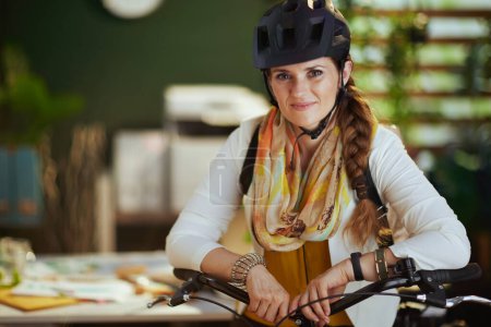 Photo for Portrait of stylish business woman in bike helmet with bike in modern eco office. - Royalty Free Image