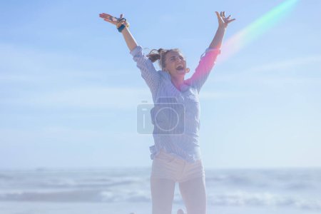 Foto de Smiling elegant female at the beach rejoicing and jumping. - Imagen libre de derechos