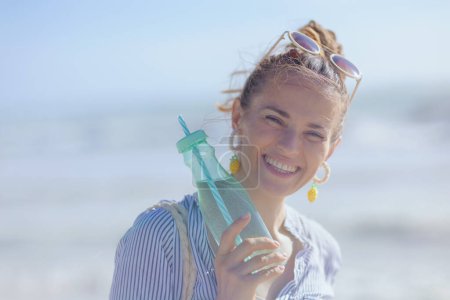 Photo for Portrait of happy elegant middle aged woman with drink at the beach. - Royalty Free Image