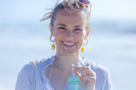 Photo for Portrait of happy elegant middle aged woman with drink at the beach. - Royalty Free Image