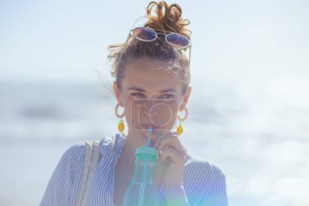 Téléchargez les photos : Modern female with drink at the beach. - en image libre de droit