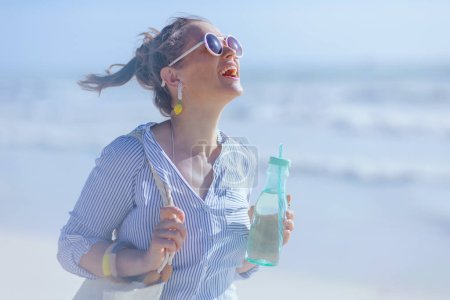 Photo for Smiling stylish middle aged woman with drink at the beach. - Royalty Free Image
