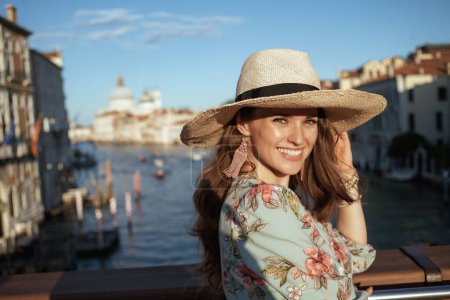 Téléchargez les photos : Portrait of happy elegant woman in floral dress with hat on Accademia bridge in Venice, Italy. - en image libre de droit