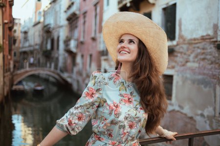 Téléchargez les photos : Smiling young tourist woman in floral dress with hat enjoying promenade in Venice, Italy. - en image libre de droit