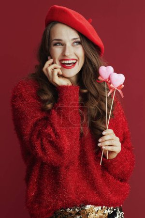 Foto de Happy Valentine. smiling elegant 40 years old woman in red sweater and beret with hearts on stick. - Imagen libre de derechos