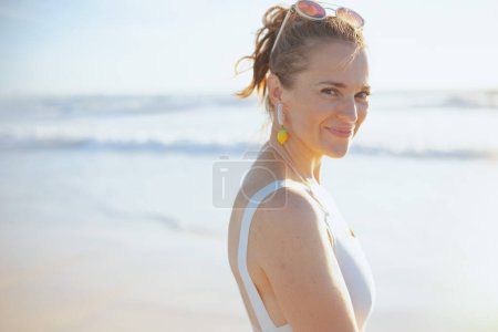 Photo for Portrait of smiling modern middle aged woman in white beachwear at the beach relaxing. - Royalty Free Image