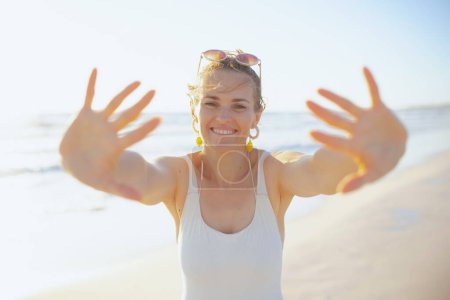 Foto de Smiling modern woman in white beachwear at the beach having fun time. - Imagen libre de derechos