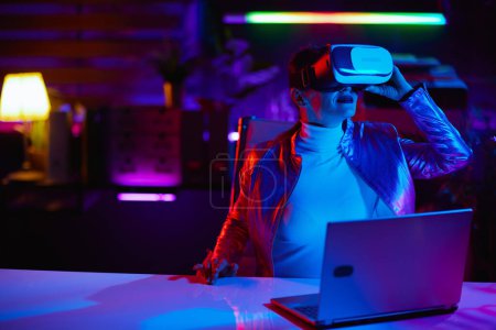 Photo for Neon metaverse futuristic concept. stylish female in vr headset in modern office. - Royalty Free Image